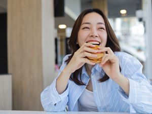 Woman smiling while enjoying sandwich outside