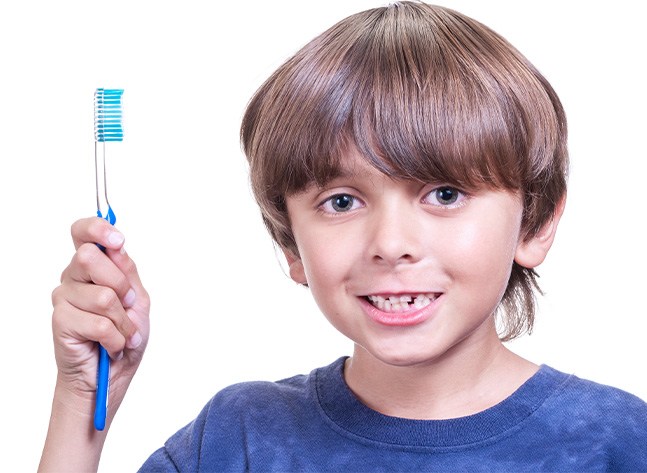 Young boy with misaligned teeth holding a toothbrush