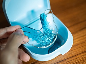 Patient placing blue retainer in blue case