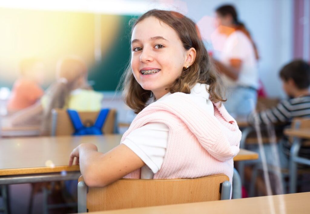 A girl with braces sitting in a classroom.